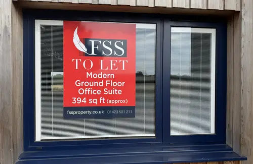 The front window of Fields Edge office Unit 23 with the Estate Agents To Let sign in it.